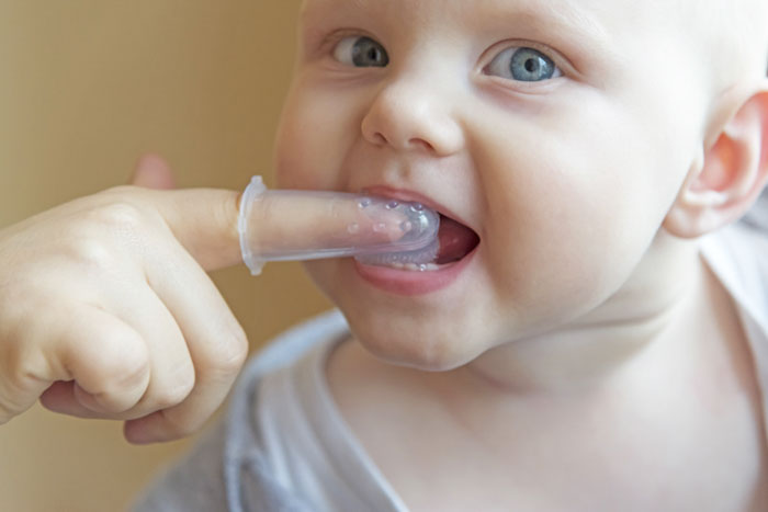 Dùng bàn chải mềm loại gắn vào ngón tay để làm sạch răng cho trẻ